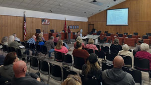 SCTTA speaks to a seated audience inside Wayne County meeting room, with a projected slide titled “Partner Benefits” displayed at the front of the room.
