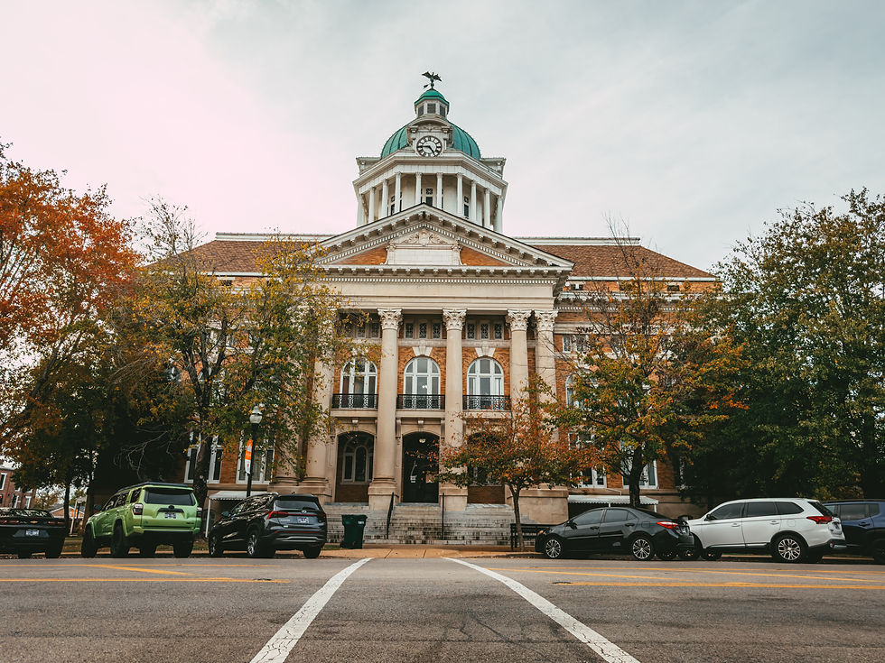 The historic Giles County Courthouse stands prominently in downtown Pulaski, framed by autumn trees and parked cars.