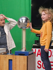 A child smiles as a Van de Graaff generator makes her hair stand on end during a live science demonstration at the Hands-On Science Center.