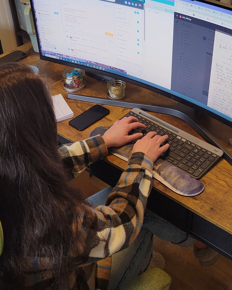 A woman in plaid sitting at a keyboard typing.