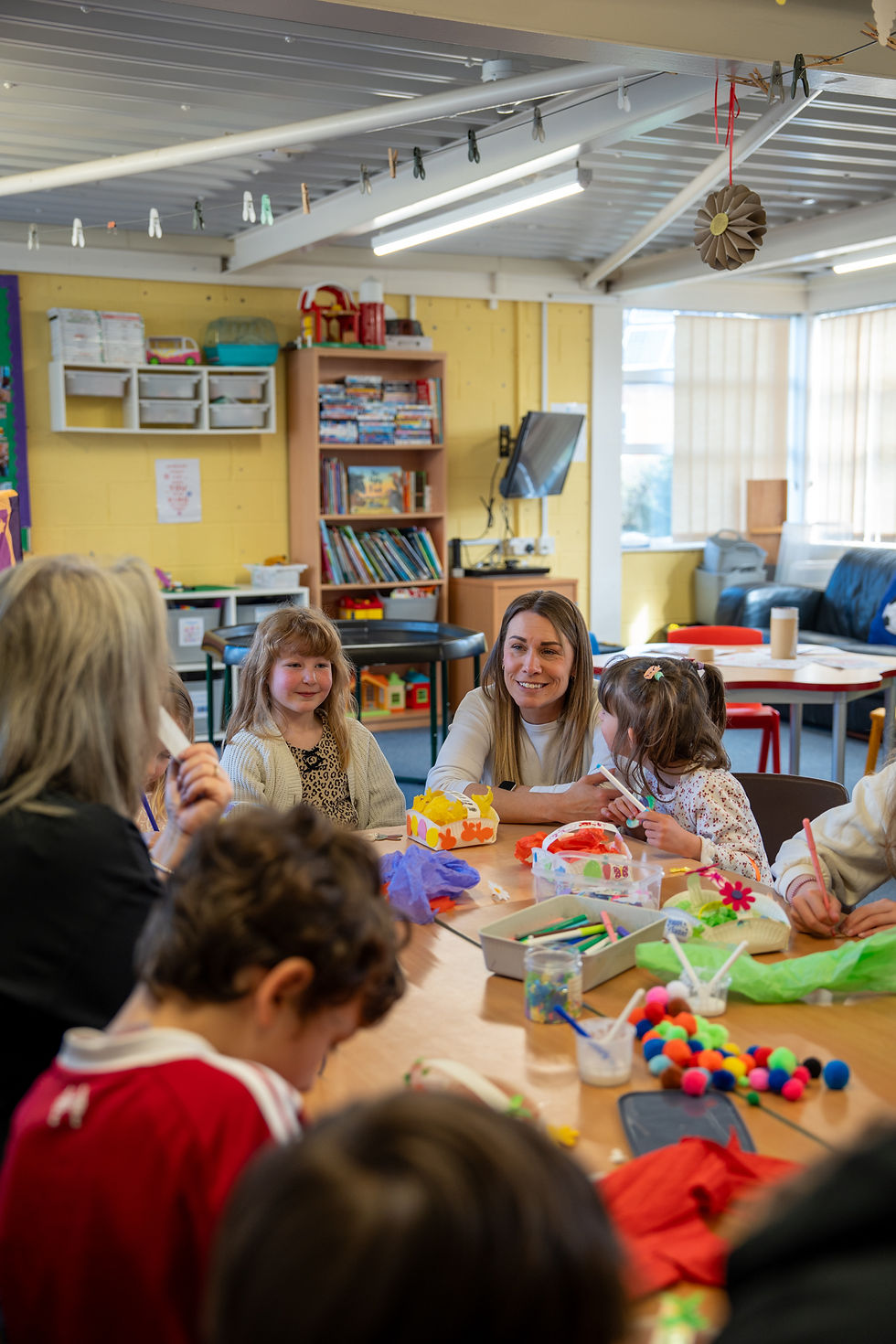 Staff member sitting at a table with children doing crafts