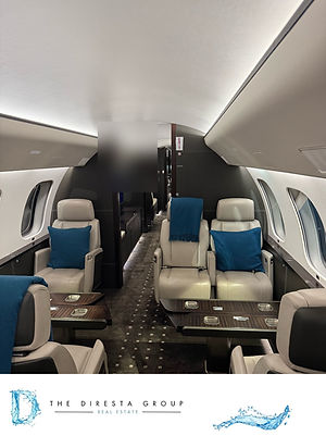 Club seating with teal cushions and dining tables in a large-cabin jet