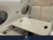 White private jet cabin with cream leather club seats and a fold-out conference table beneath oval windows