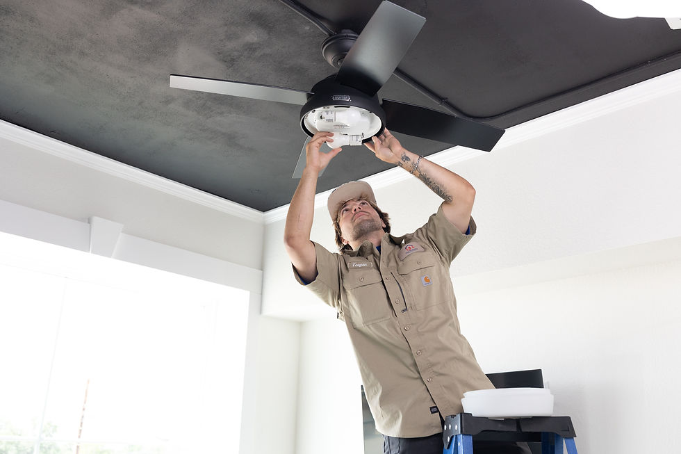 Electrician installing a ceiling fan light fixture in a white room. Services available.