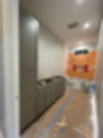 Bathroom under construction with grey cabinetry and tub.
