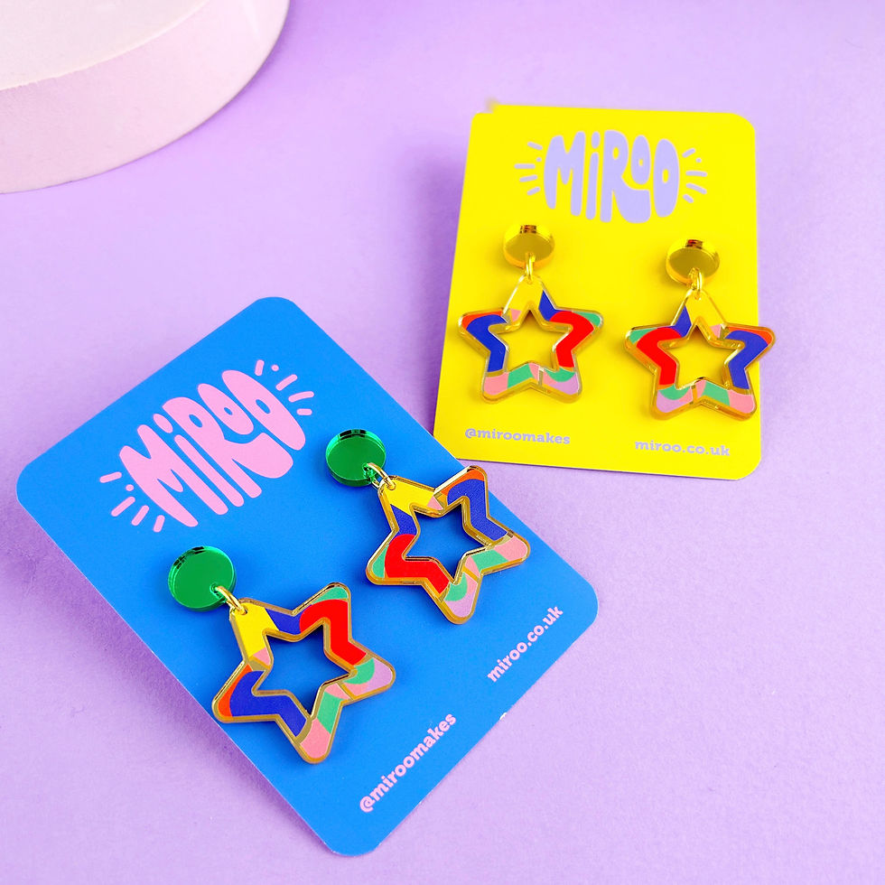 Thumbnail: A pair of colourful star shaped earrings. Dangle earrings made from mirrored gold acrylic with colourful pattern