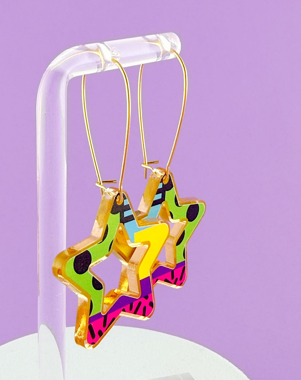 Thumbnail: side shot of star earring in green, blue, yellow, purple and pink abstract pattern, set in mirrored gold acrylic frame