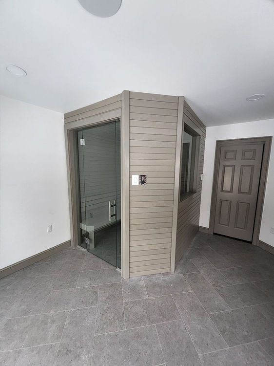 Custom Indoor Sauna with Glass door and Modern gray wood built into a large existing room.