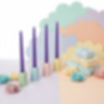 Four pure beeswax coloured taper candles in holders on a table set for a birthday party.