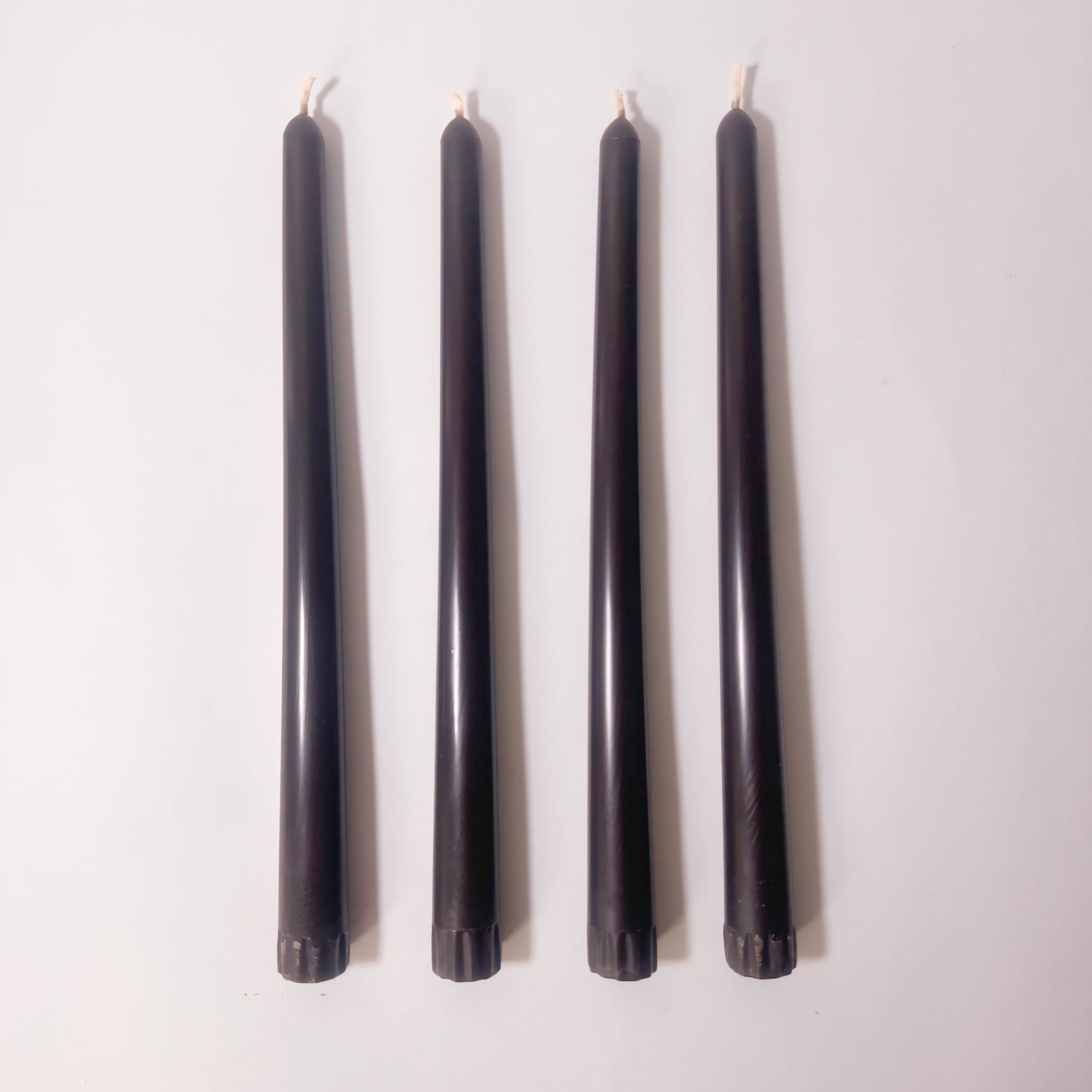 Four pure beeswax taper candles in colour Burnt Umber, top view.
