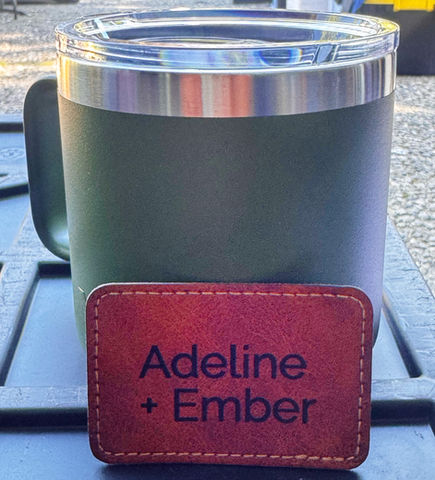 Green mug with handle and leather tag says Adeline + Ember on table.