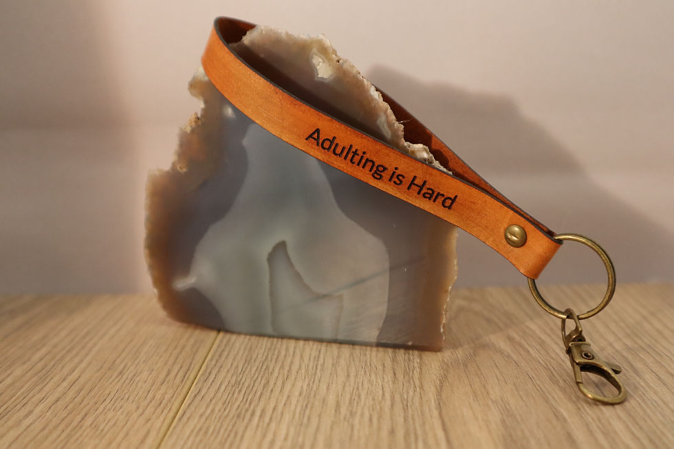 Thumbnail: Leather wristlet key chain with "Adulting is Hard" message against stone.