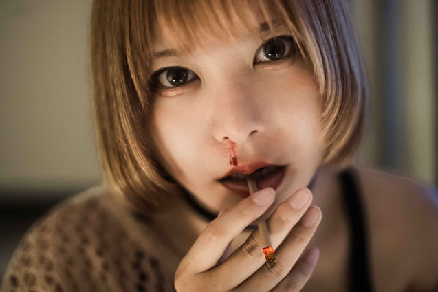 A dark-toned, dramatic close-up fine art portrait of model Konami Sano from Yuichi Nakamura's series "Homage to LEON," exhibited at PASHA STYLE Cross Exhibition 5. The subject portrays the iconic heroine with an intense, cinematic gaze, capturing the profound emotional depth and character narrative.