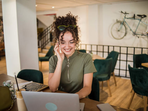 Getty image of woman on phone in front of laptop. (Source: Microsoft Blog, "Turning customer experience into a growth engine" April 27, 2026)