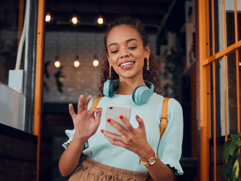 Person using a smartphone in a café setting, representing everyday customer engagement on WhatsApp as highlighted in the Genesys announcement.