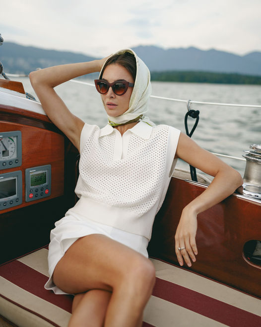 Woman wearing sunglasses and headscarf on a boat, mountain background. Jenia Ria