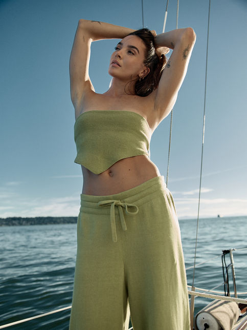Woman in green strapless knit top with arms raised, sailboat knitwear campaign photoshoot