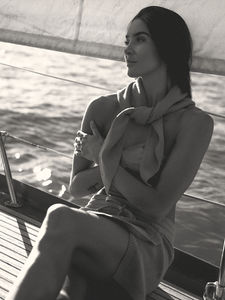 Woman in a knit skirt and scarf on a sailboat, arms crossed, campaign photoshoot for knitwear brand Ahblo