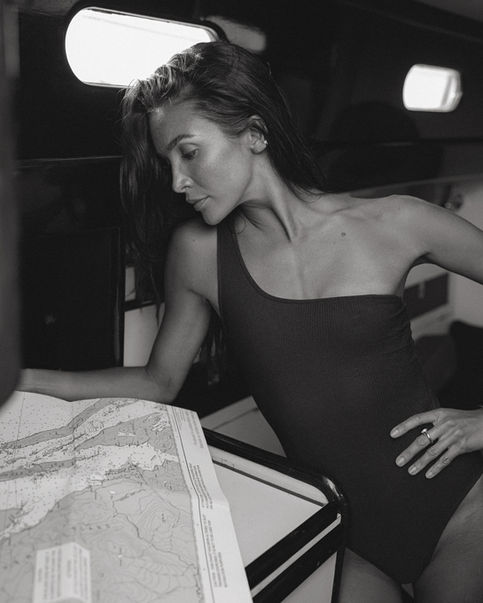 Woman in a swimsuit looks at a map inside a boat, Jenia Ria, black and white photo