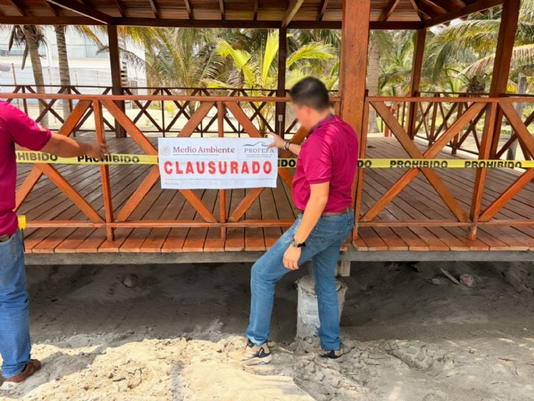 Official PROFEPA federal closure seals posted on concrete pillars and construction machinery at a seaside building site in Baja California Sur.