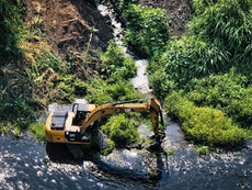 Excavadora trabajando en el cauce de un arroyo en Los Cabos, removiendo arena y desechos para permitir el libre flujo del agua durante las lluvias.