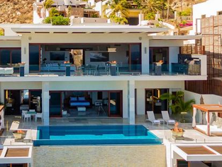 A modern luxury home on the coast of Los Cabos, with its windows secured, withstanding the high surf and cloudy sky of a storm.
