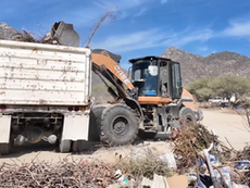 Camiones de servicios públicos de Los Cabos recolectando muebles viejos, llantas y cacharros en una zona residencial, con trabajadores municipales barriendo las calles para mejorar la imagen urbana.