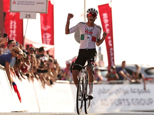 El ciclista mexicano Isaac del Toro celebrando con el maillot rojo de campeón en el podio del UAE Tour 2026, rodeado de sus compañeros de equipo.