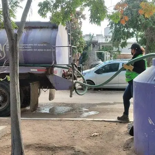 "Purple Tanker" unit performing irrigation work in a public park in La Paz, showcasing the use of treated water for green areas.