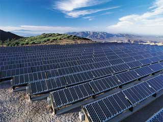 Una hilera de modernos paneles solares instalados en el techo de una vivienda residencial bajo el intenso sol y cielo despejado de La Paz, Baja California Sur.