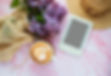 Cup of coffee, lilac flowers and e-reader with copy space on pink marble background Templa