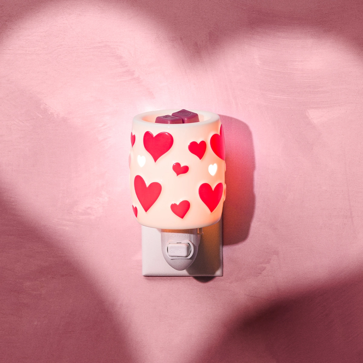 Heartstruck Miniduftlampe der Scentsy Valentinstag Kollektion 2026. Weiße RundeDuftlampe aus leuchtender Keramik mit roten Herzen