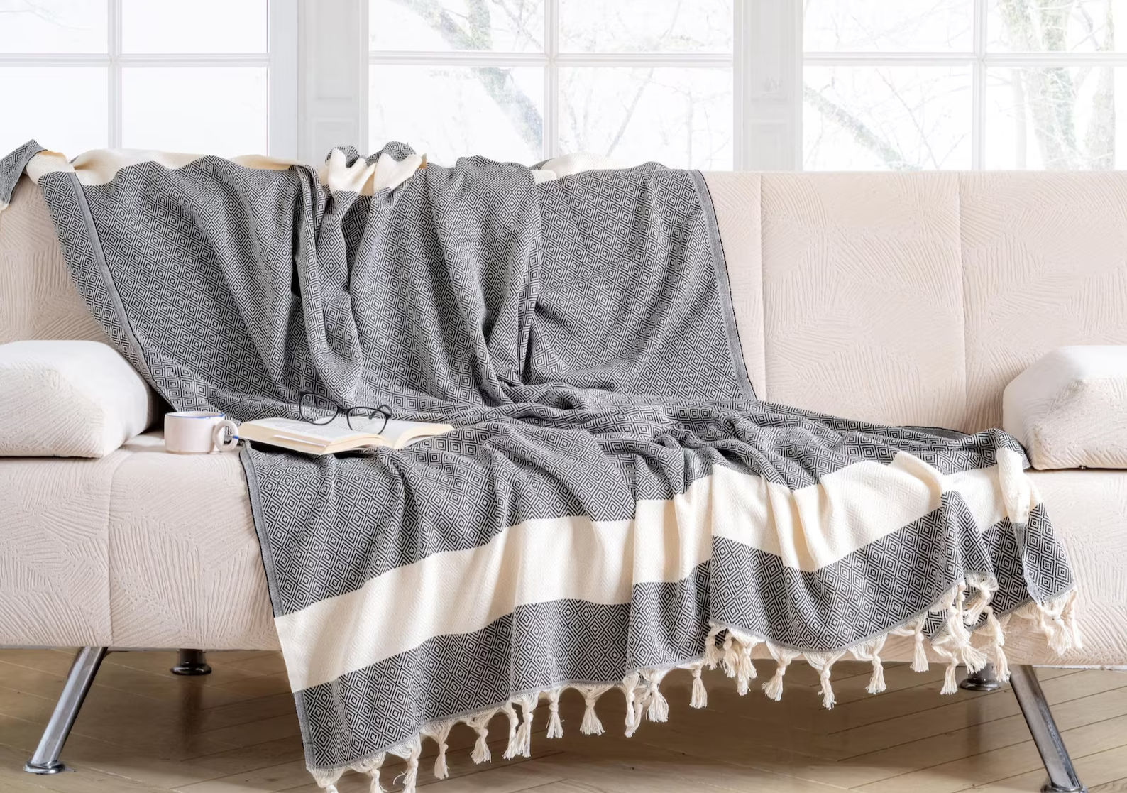 Gray and white striped Diamond Blanket draped over a cream colored sofa. Cozy Peshtemal Concept