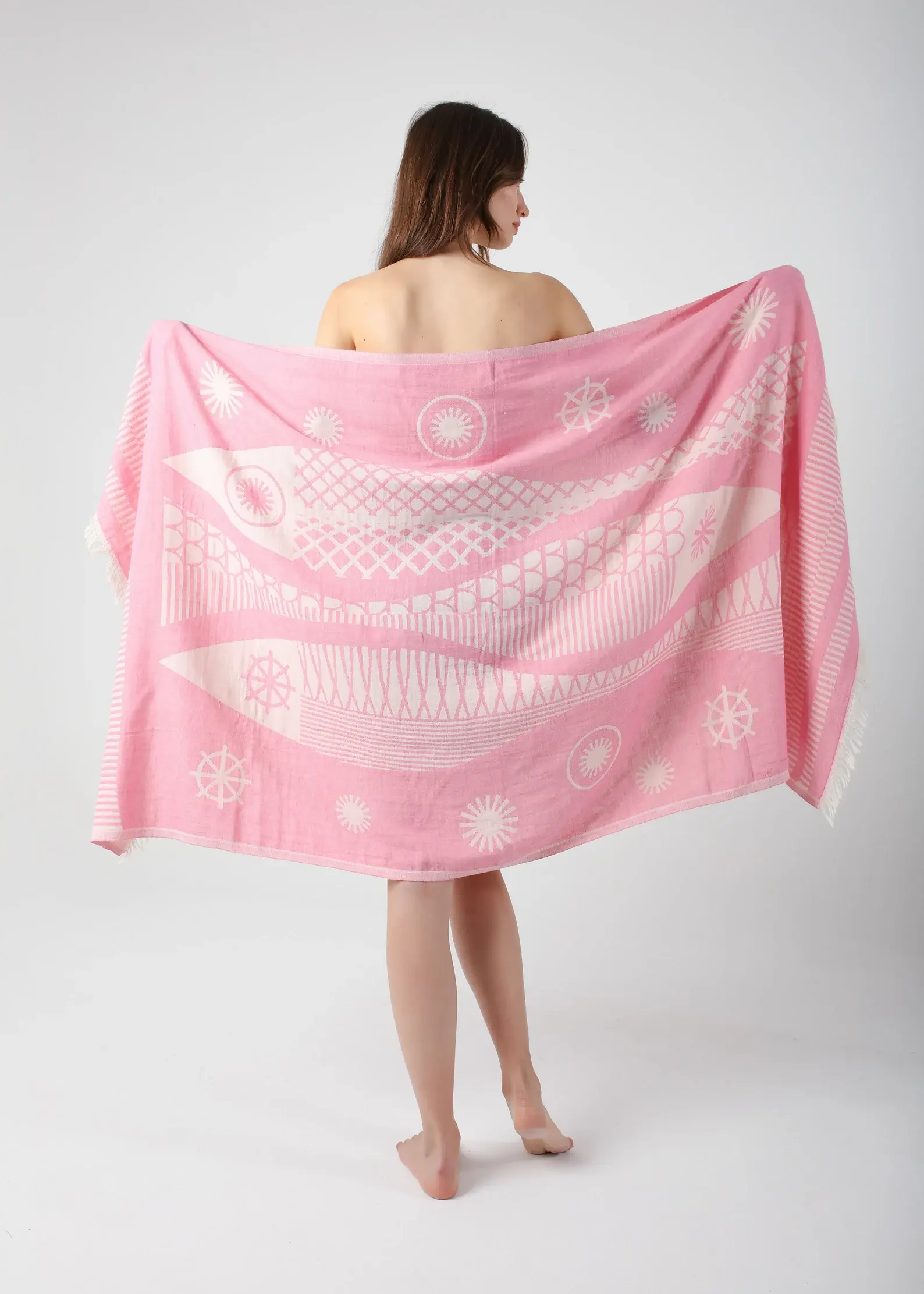 Woman holding pink Santa Barbara Turkish towel, peshtemal concept, white background.