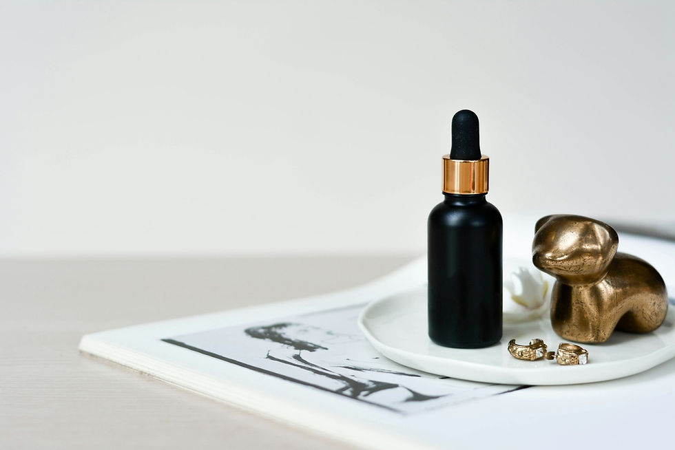 A dark dropper bottle with gold detailing photographed on a neutral background
