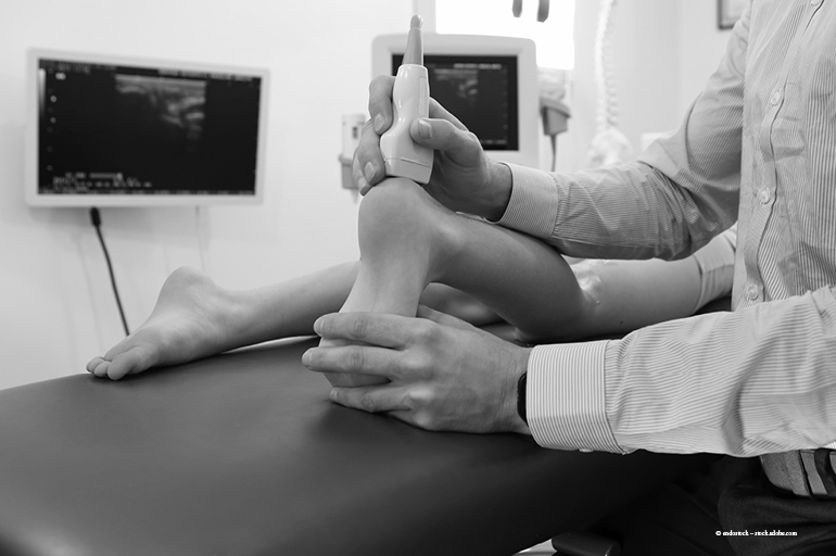 Clinician performing musculoskeletal ultrasound on the ankle using a linear probe