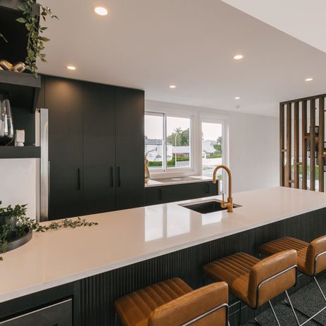 Modern black and white kitchen in new build home featuring matte black cabinetry, white stone benchtops, gold tapware, integrated appliances, and designer pendant lighting—highlighting custom interior design and premium home construction.