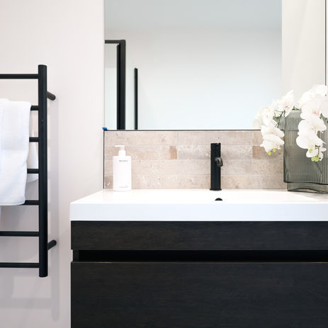 Modern bathroom with black wall-hung vanity, matte black tapware, square mirror, with black heated towel rail – stylish and functional design for contemporary home builds.