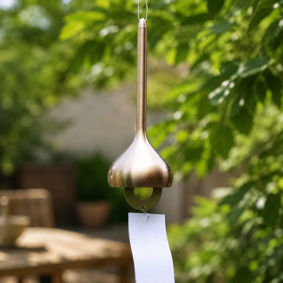 Miniatura: Detalle de campana de viento japonesa Viento Alto dorada suspendida entre vegetación