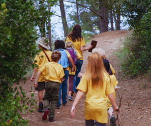 Kids hiking in the woods, exploring nature at camp.