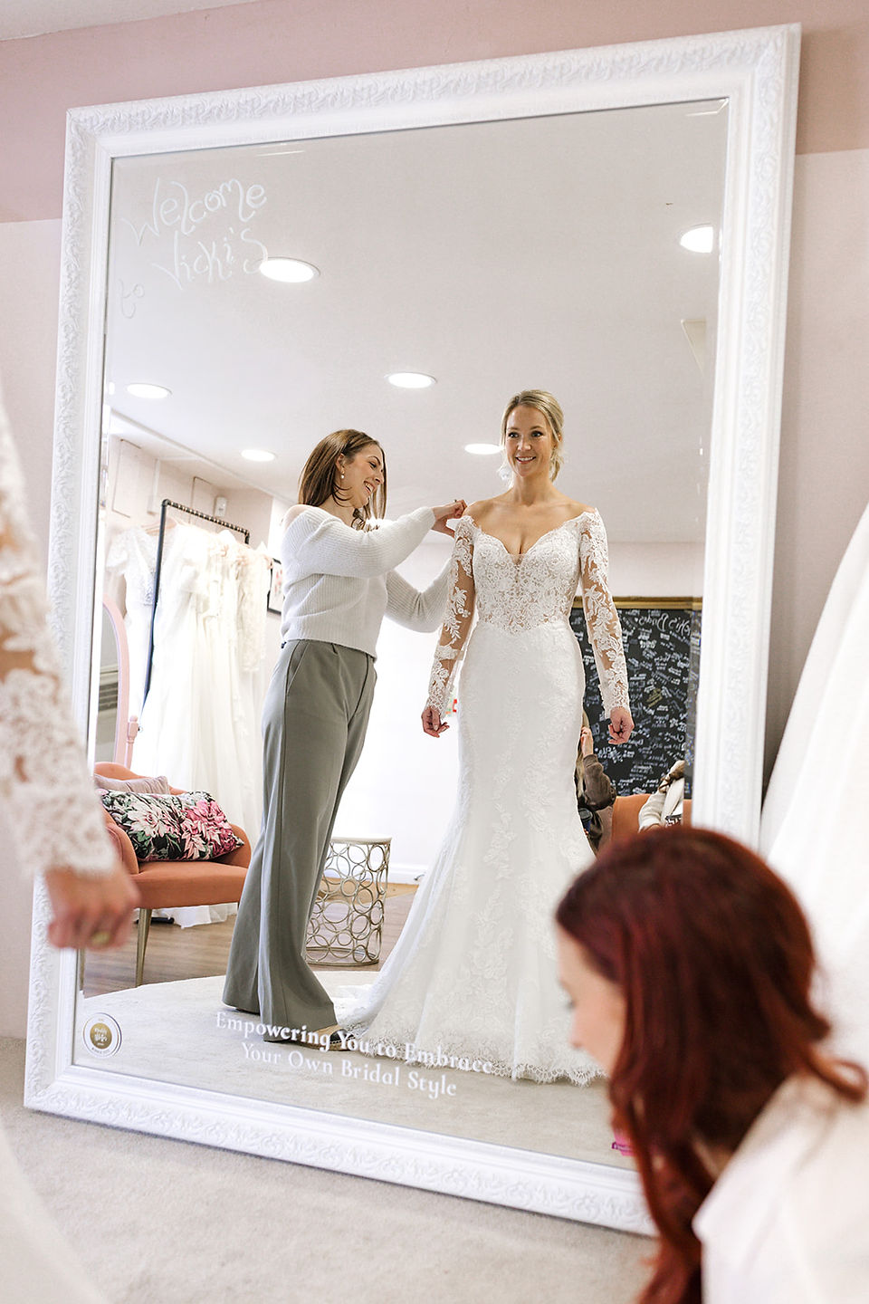 bride looking in a mirror wearing a lace fitted dress