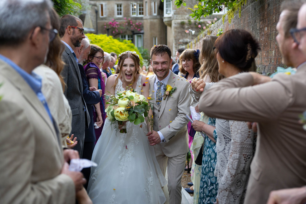 bride and groom smiling running through a crowd