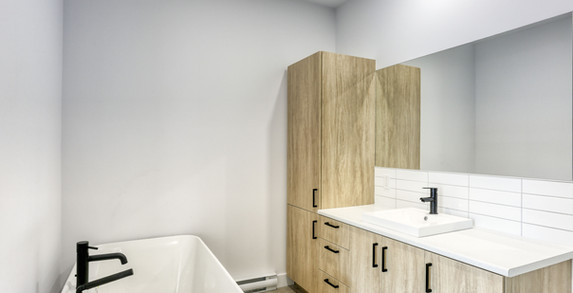 Baignoire moderne et meuble lavabo en bois dans l’appartement à louer à Terrasses Saint-Maurice.
