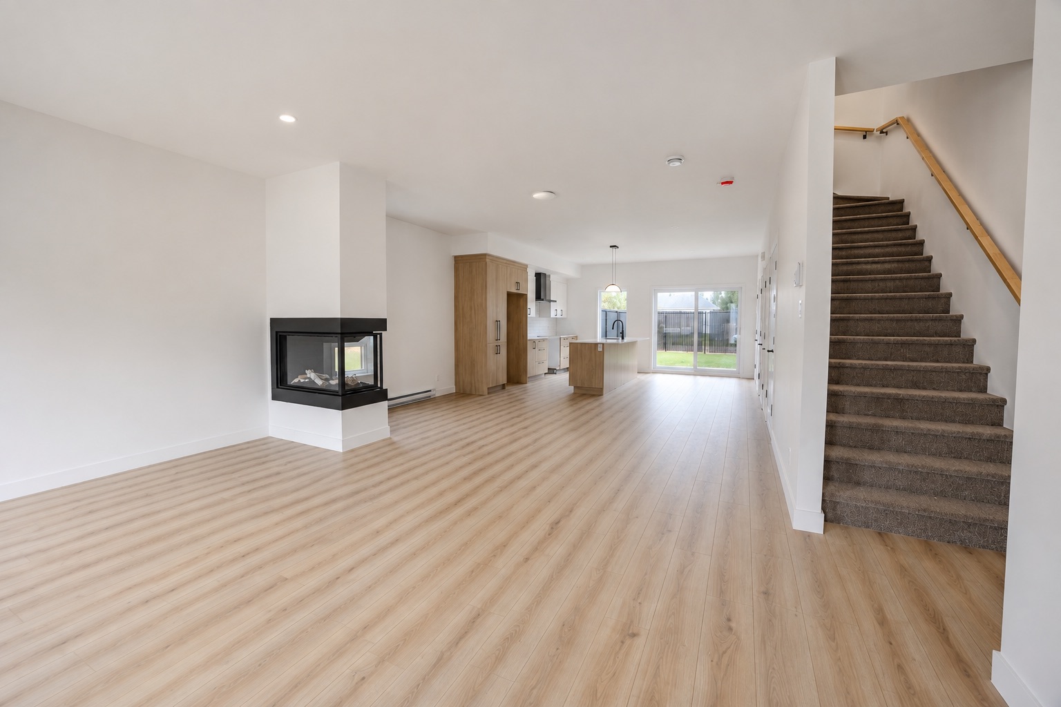 Aire de vie ouverte avec foyer, cuisine et escalier dans une maison de ville 4 ½ à Saint-Boniface.