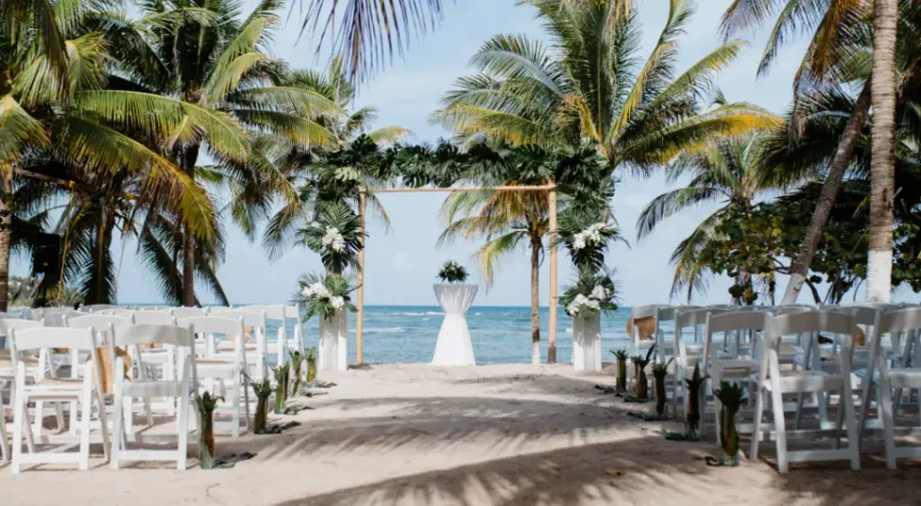Luxury wedding ceremony setup on the beach in Riviera Maya with palm trees and ocean view.