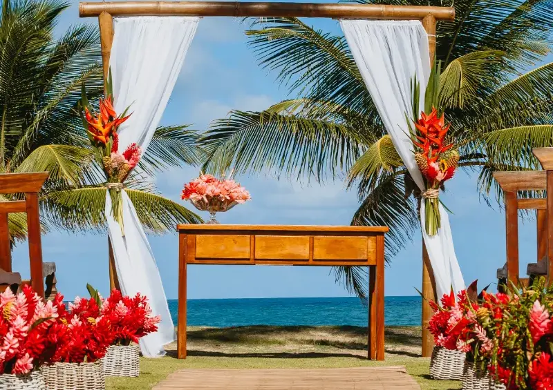 Tropical beachfront wedding altar with palm trees and floral decor in Riviera Maya.