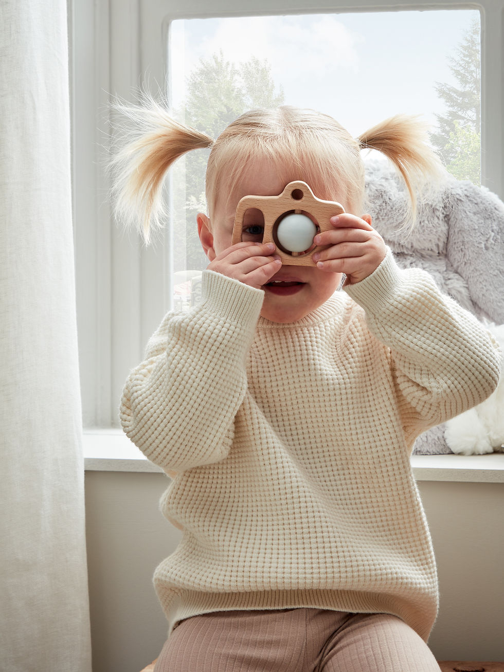 young girl playing with wooden camera