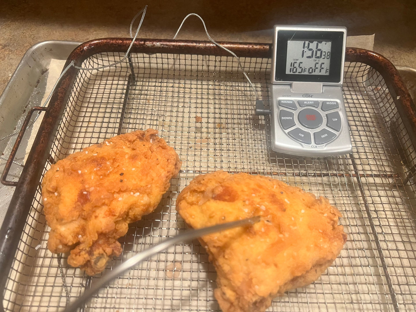 Protein seasoned and draining on paper towel lined plate, with thermometer showing proper
