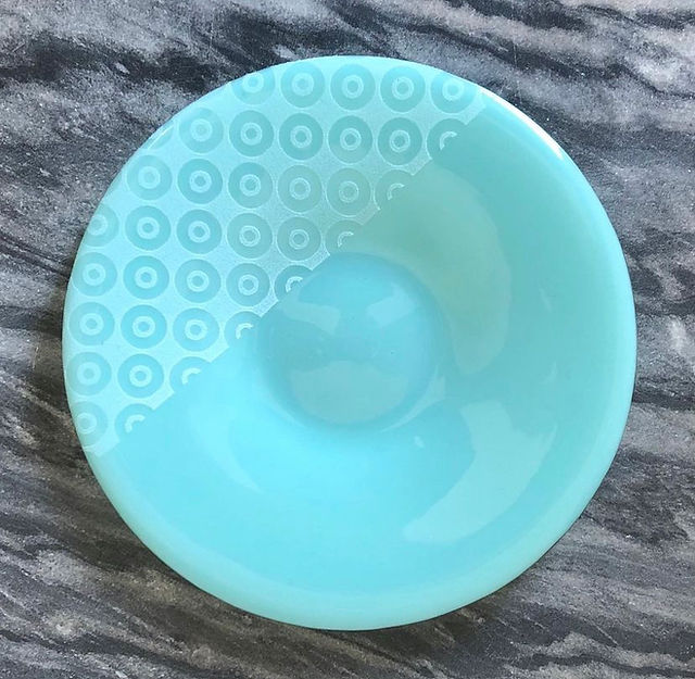 A fused and slumped glass art plate with tack fused pattern