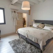 Beautiful bedroom with a King size grey bed and natural colored beddings a fluffy carpet and white walls. 
